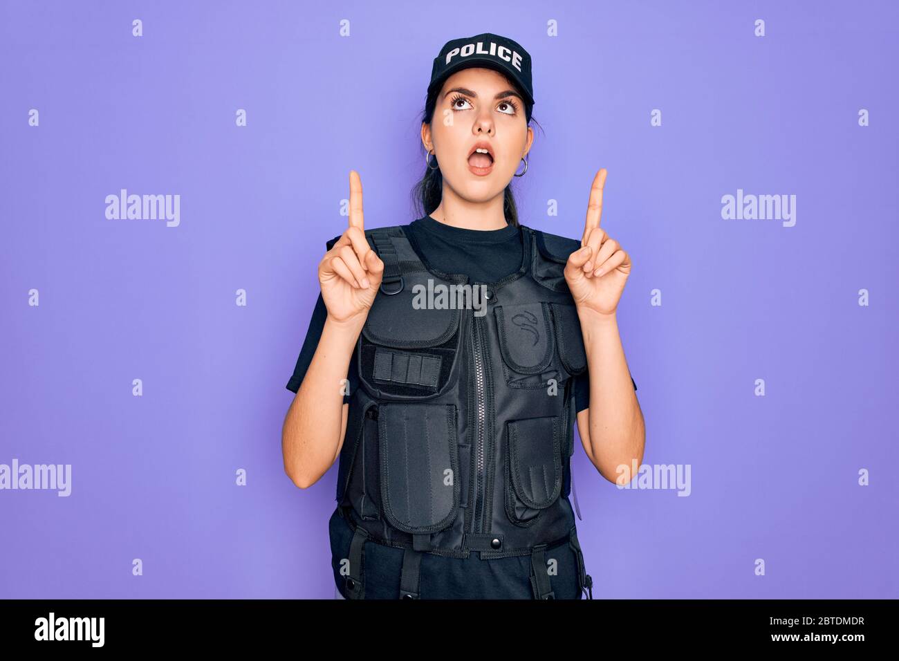 Young police woman wearing security bulletproof vest uniform over ...