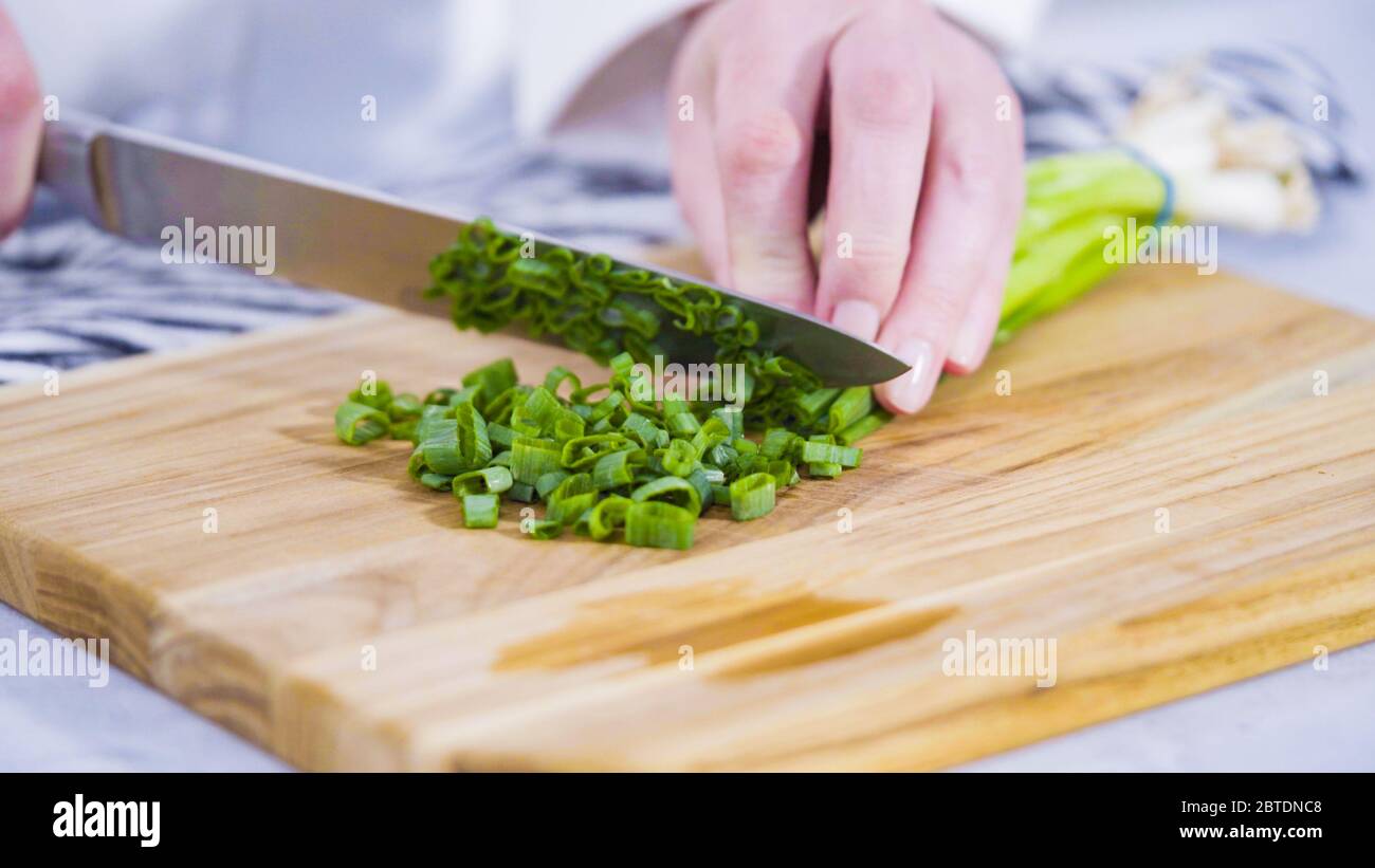 Step by step. Chopping organic green onions on a wood cutting board ...