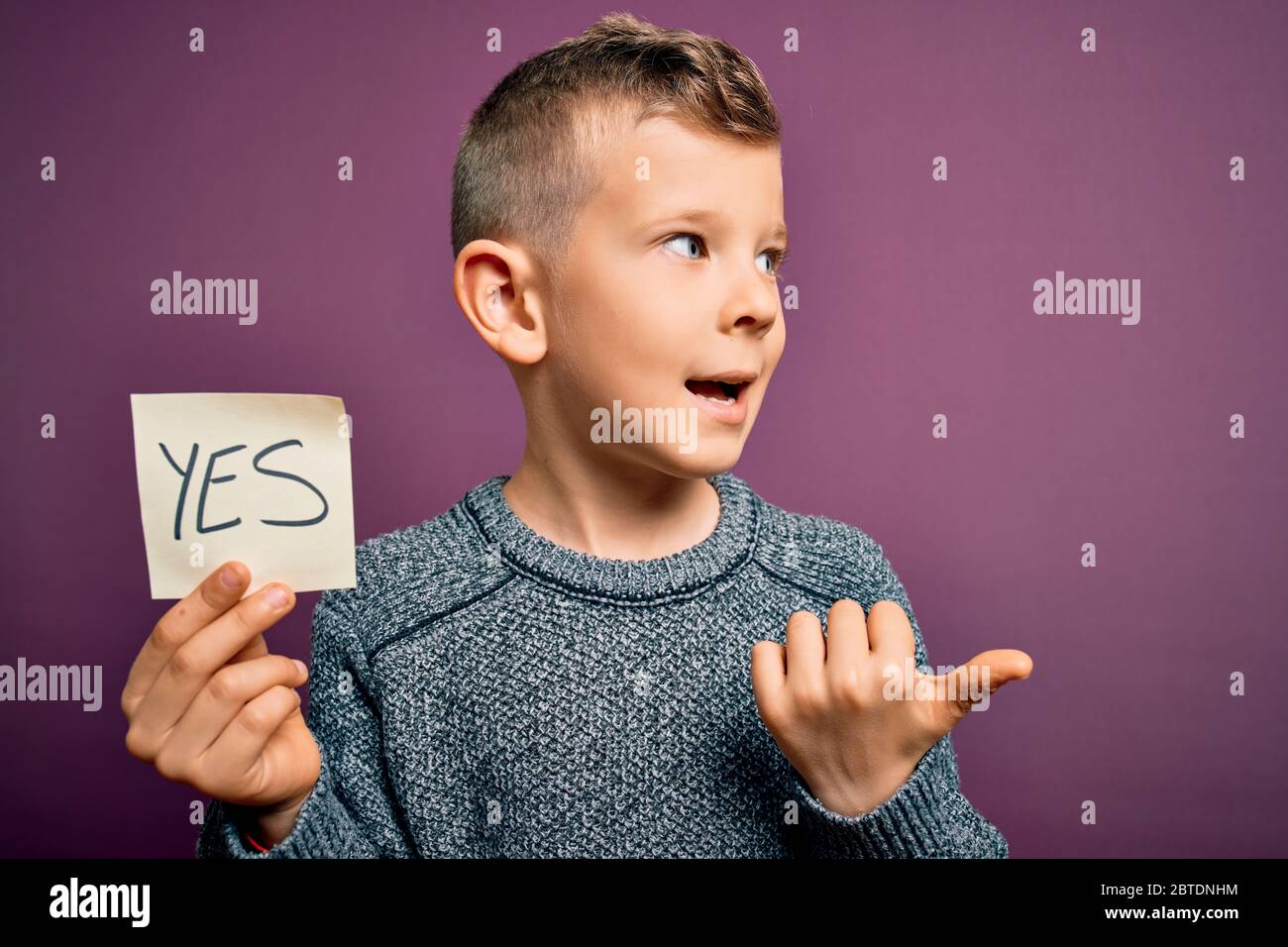 Young little caucasian kid showing YES word on a paper note as positive ...
