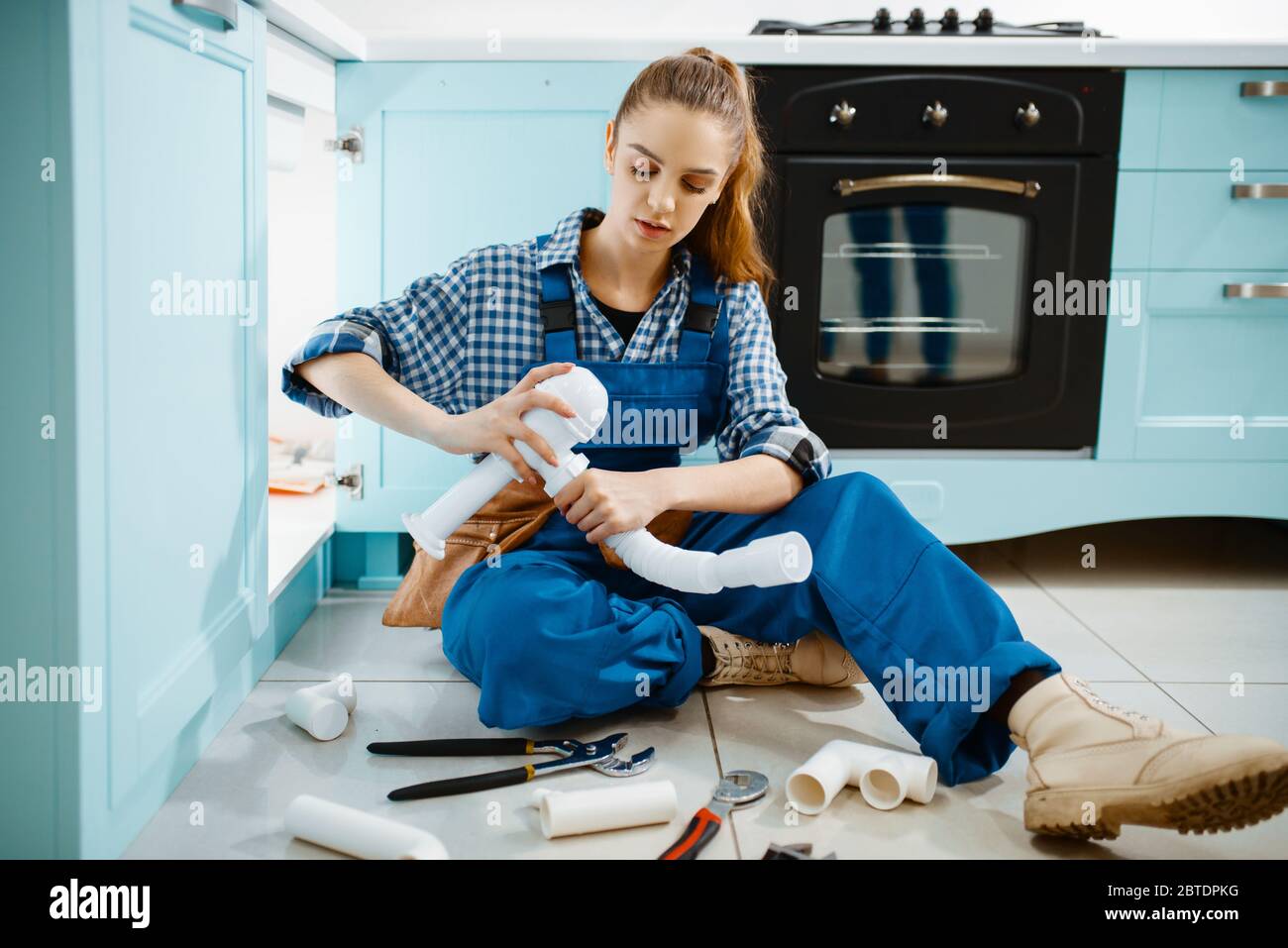 Female plumber fixing problem with drain pipe Stock Photo