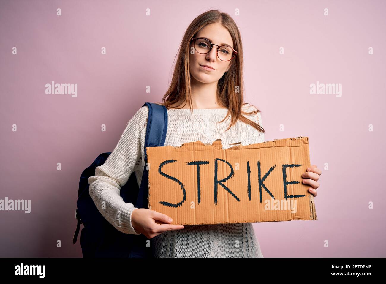 Young beautiful redhead activist woman holding banner with strike ...