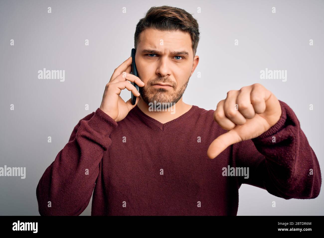 Young man with blue eyes speaking on the phone having a conversation on ...