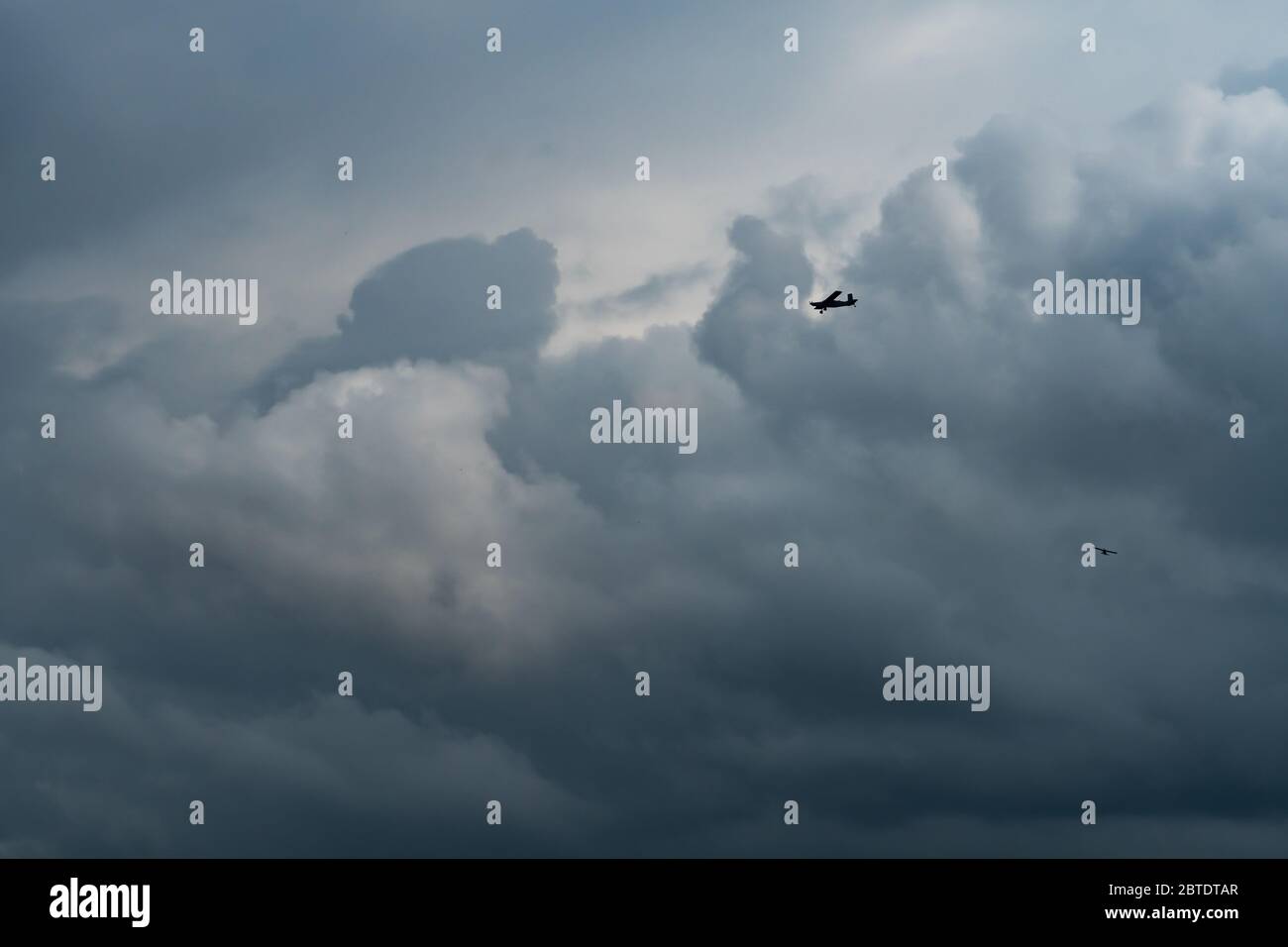 Small plane in cloudy sky for rainmaking. White fluffy clouds with small aircraft to make artificial rainfall. Two airplane flying on cloudy sky. Stock Photo