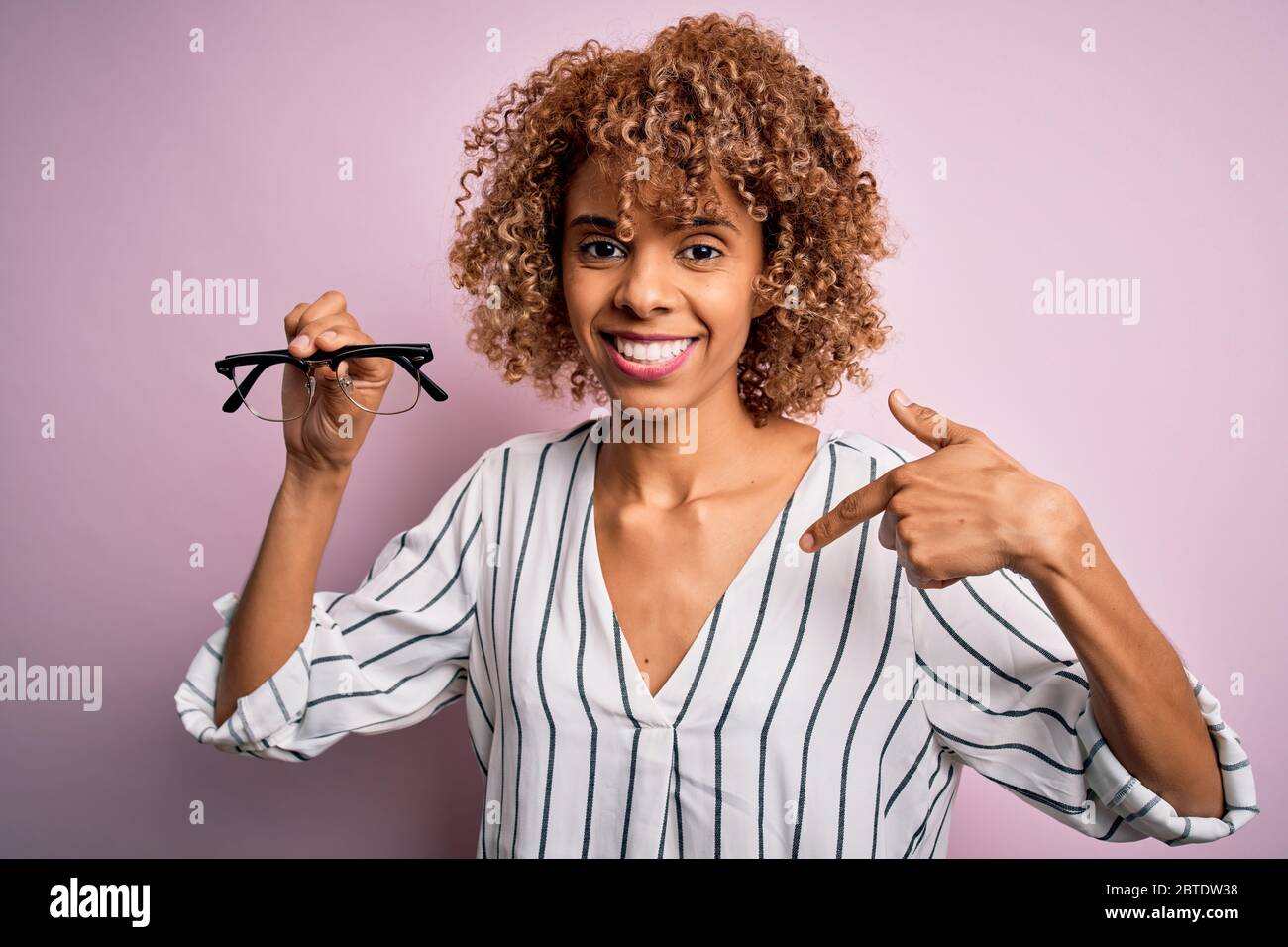 African american optical woman with curly hair holding glasses over ...