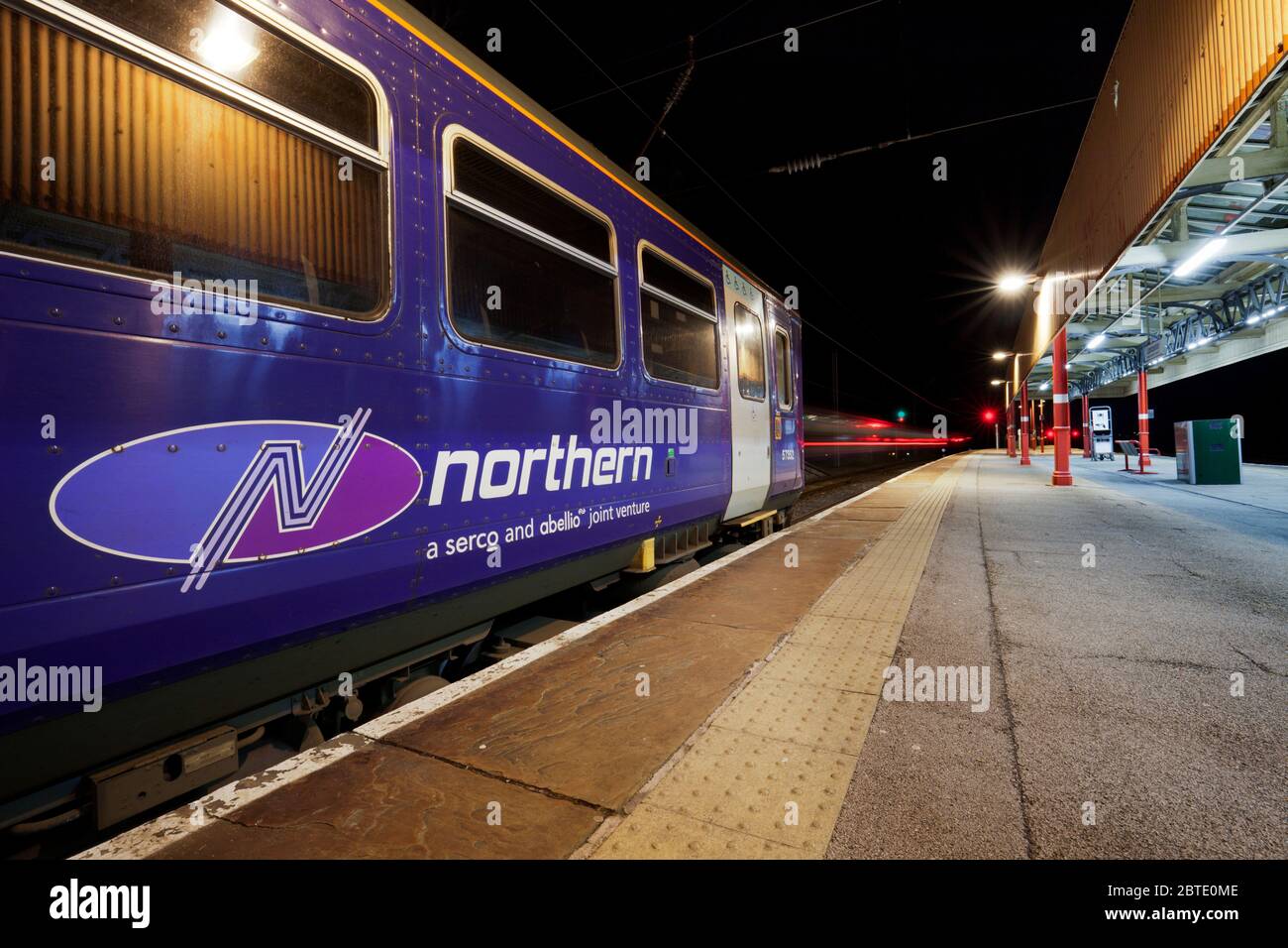 Serco Abellio Northern Rail logo on a class 153 single carriage train with light trails from another departing train. Stock Photo