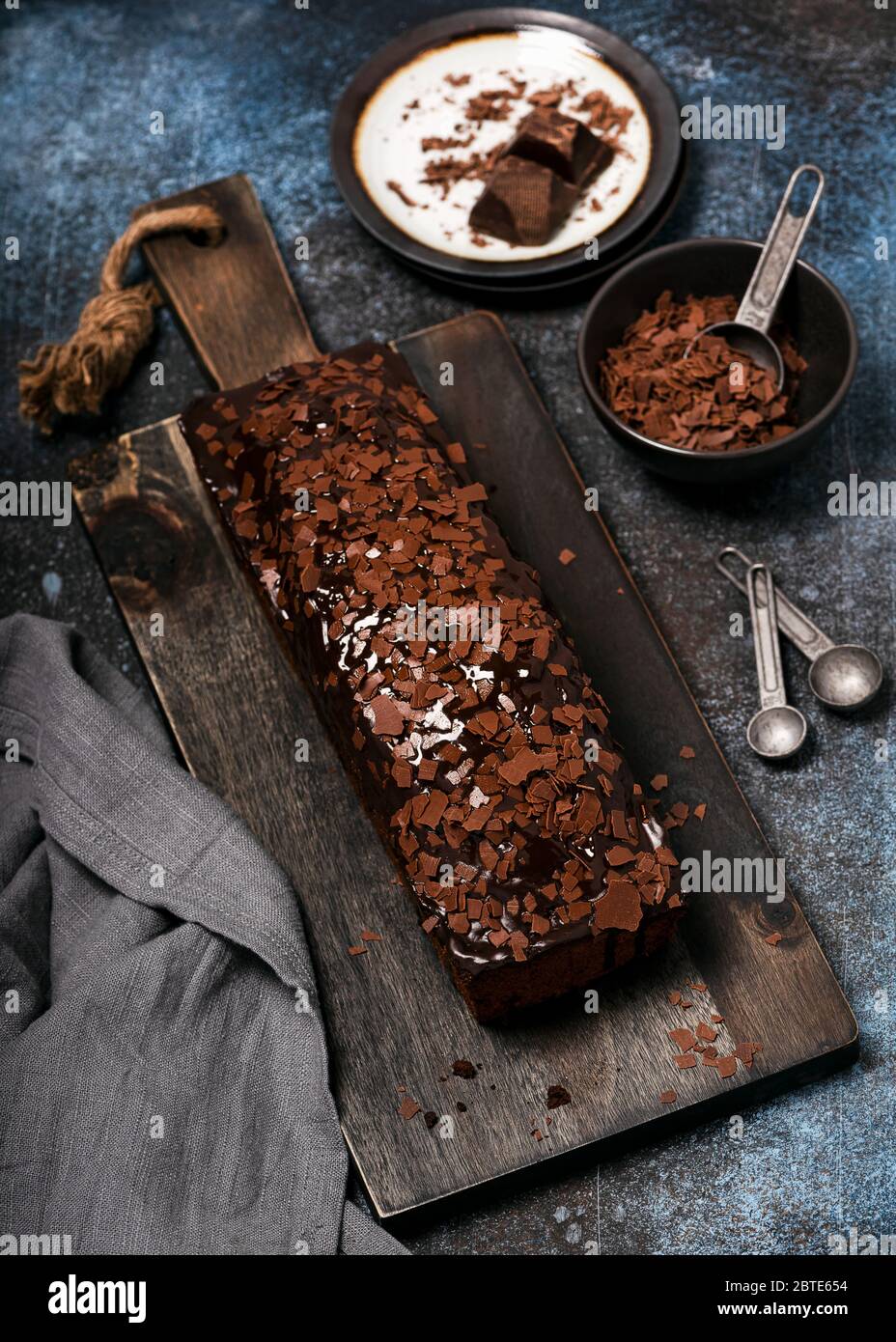 Delicious homemade chocolate cake with chips topping and glaze on rustic wooden cutting bread. Selective focus. Stock Photo