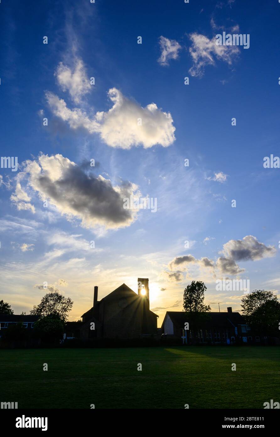 Dramatic clouds at sunset over St Johns Church in Beckenham, Kent, UK. The setting sun shines through the bell tower of the church with beautiful sky. Stock Photo