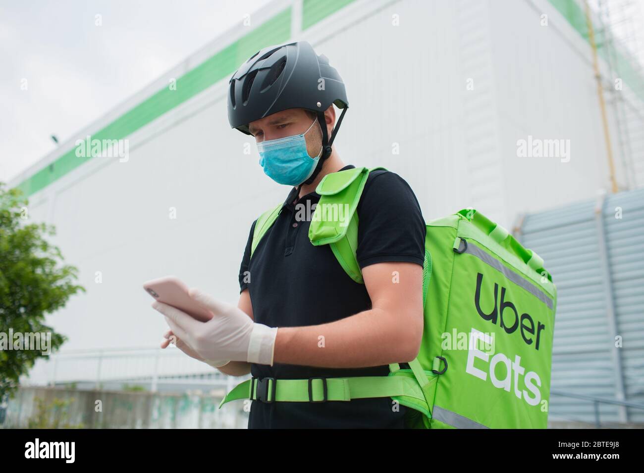 Kyiv, Ukraine - May 06, 2020: The Uber Eats courier. The food delivery  woman uses a smartphone to reach customers faster. Courier has a  refrigerator i Stock Photo - Alamy