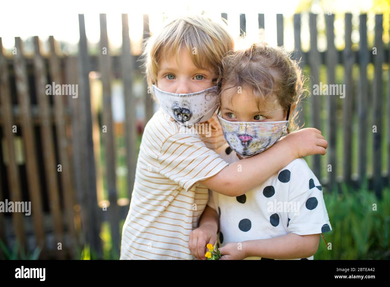 Small children with face masks playing outdoors, coronavirus concept. Stock Photo