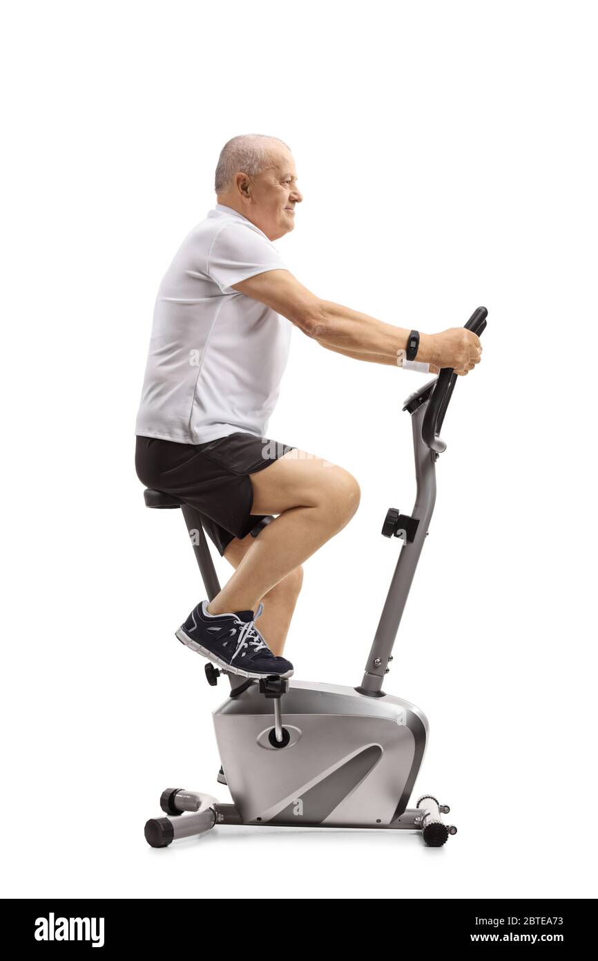 Full length profile shot of an elderly active man exercising on a stationary bike isolated on white background Stock Photo