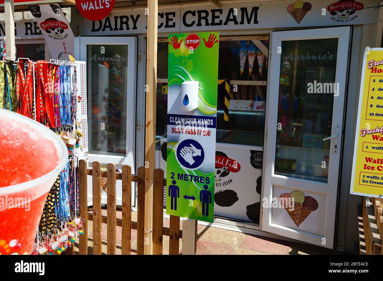 Camber, East Sussex, UK. 25 May, 2020. UK Weather: With government easing lockdown, scores of people arrive in cars and fill the car park almost immediately at Camber Sands, East Sussex. A wash station and social distancing signs outside a local ice cream parlour. Photo Credit: Paul Lawrenson/Alamy Live News Stock Photo