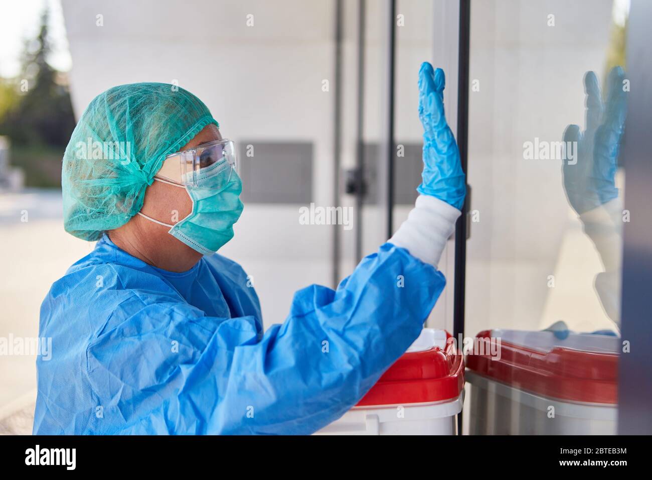 Medic in protective clothing during organ transport for surgery gives signs of admission to clinic entrance Stock Photo