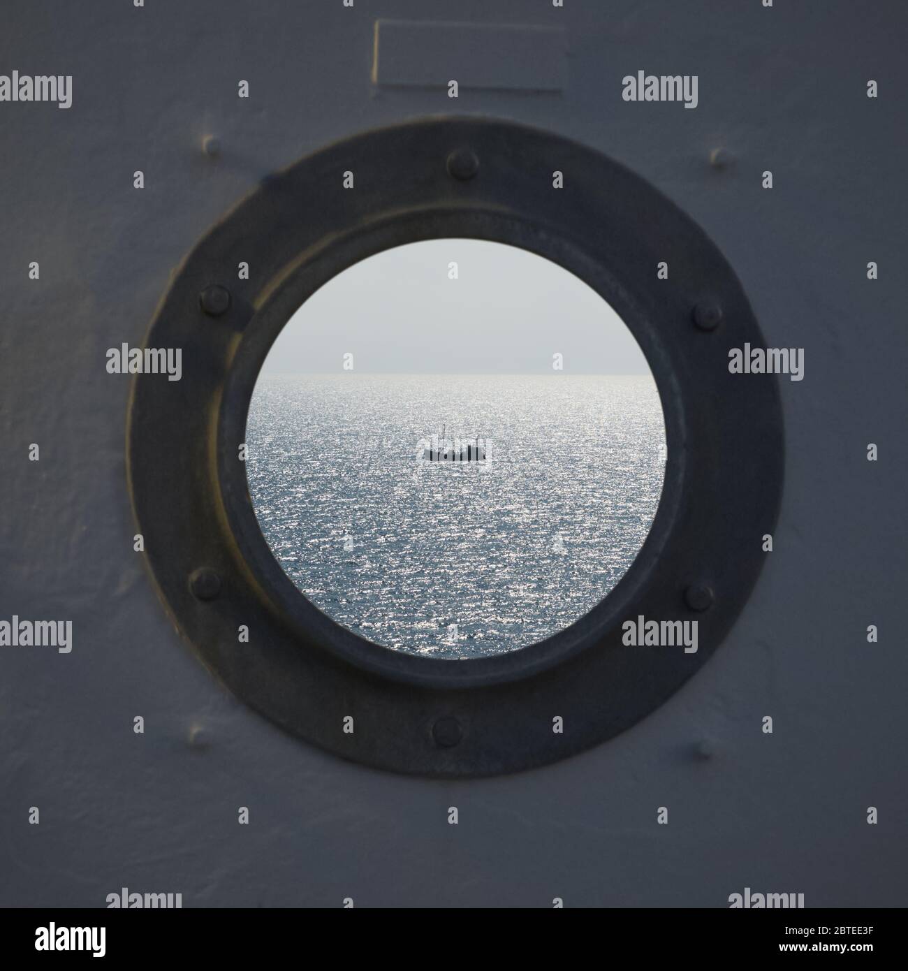 Lonely fishing ship trawler boat on ocean water. View from the round window from the cabin. Calm clear sea sunny weather. Beautiful horizon of seascape Stock Photo