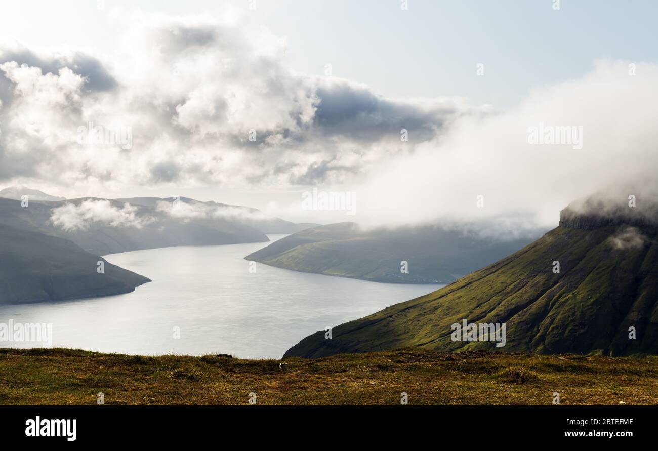 Foggy mountain peaks and clouds covering sea and mountains. Panoramical view from famous place - Sornfelli on Streymoy island, Faroe islands, Denmark. Landscape photography Stock Photo