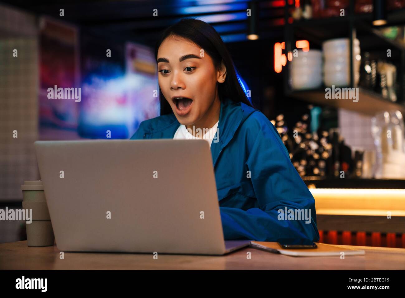 Photo of excited young asian woman working with laptop and expressing ...