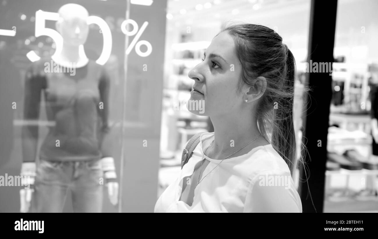Black and white portrait of beautiful smiling woman choosing new clothes in shopping mall during seasonal sale Stock Photo