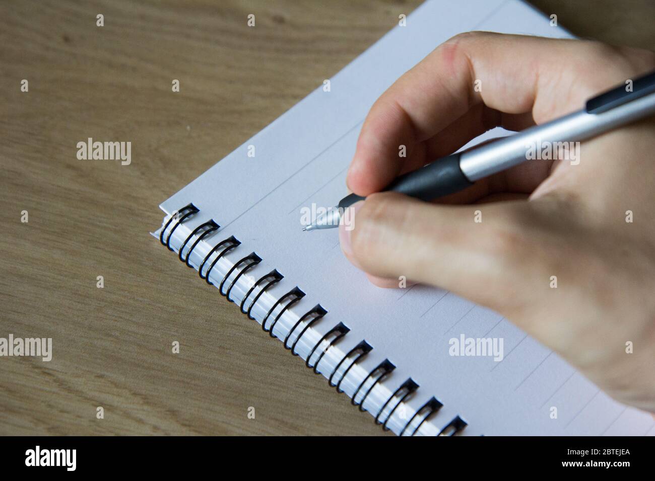 Writing into a notebook with a filling pencil. - Stock Image