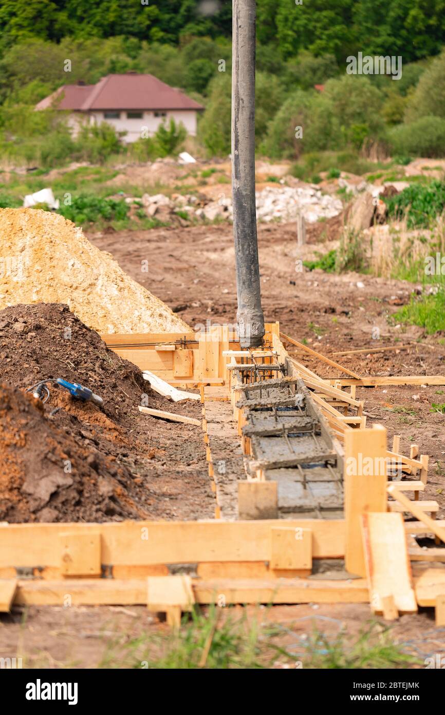 Lay of the cement or concrete into the foundation formwork with automatic  pump. Building house foundation Stock Photo - Alamy