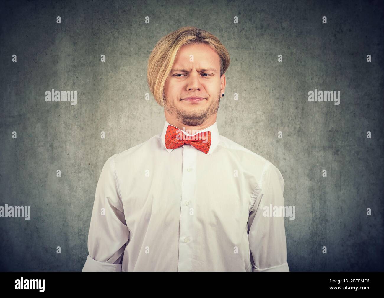 Man feeling annoyed grimacing with disgust his face isolated on grey background. Stock Photo