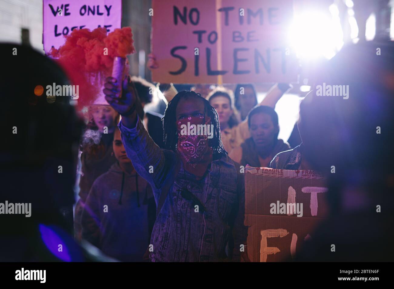 Protestors demonstrating with smoke grenades in front of the security force at night. Anti-government protest by the social activist group. Stock Photo
