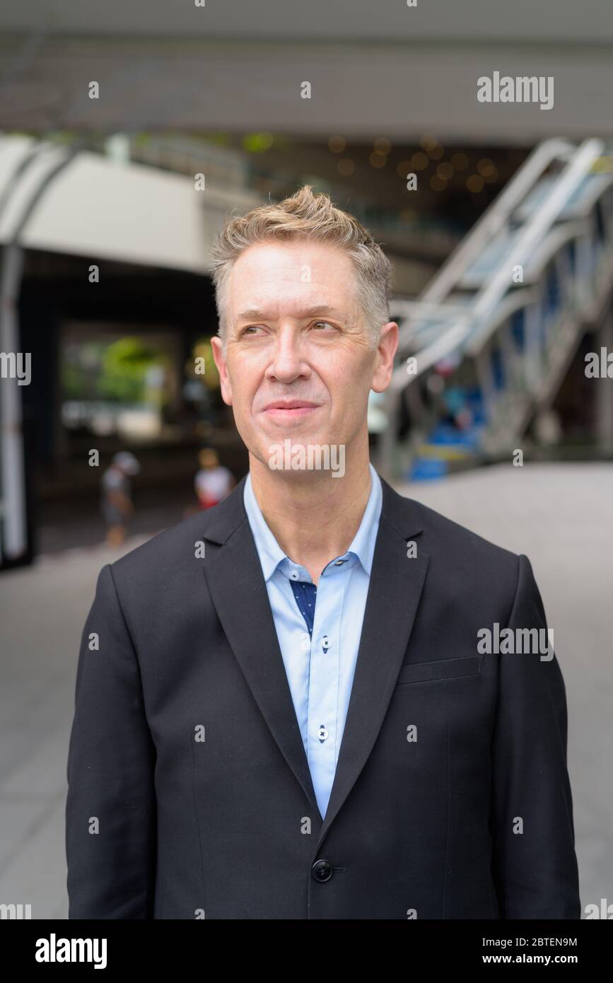 Mature businessman thinking at footbridge in the city Stock Photo - Alamy