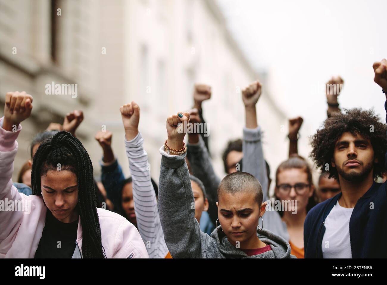 Group of protesters on the road with their arms raised. Multi-ethnic people protesting on the street. Stock Photo