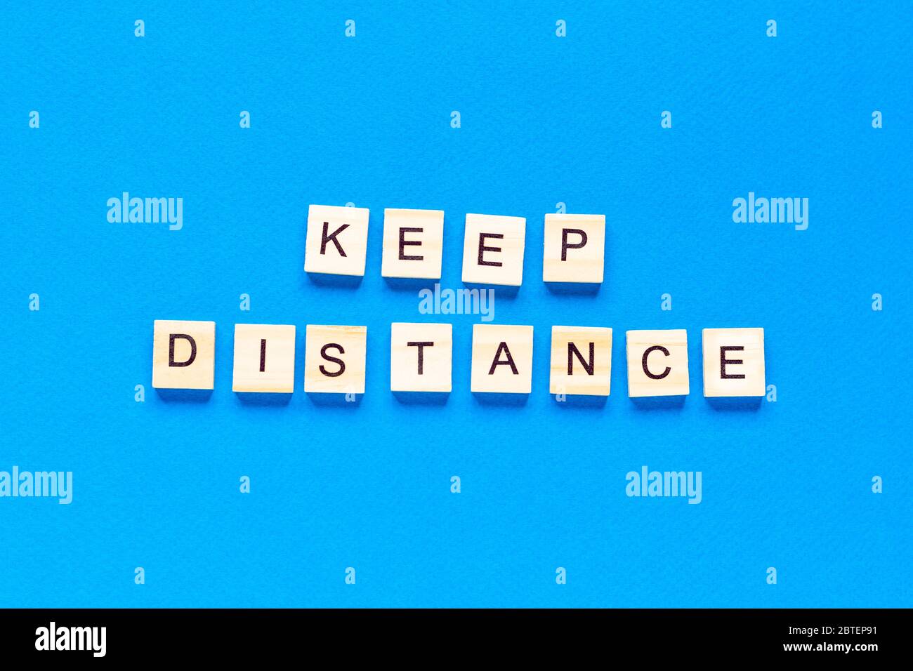 Words keep distance . Wooden inscription on a blue background. Information sign of keep distance from blocks on a blue background. top view, flat layo Stock Photo