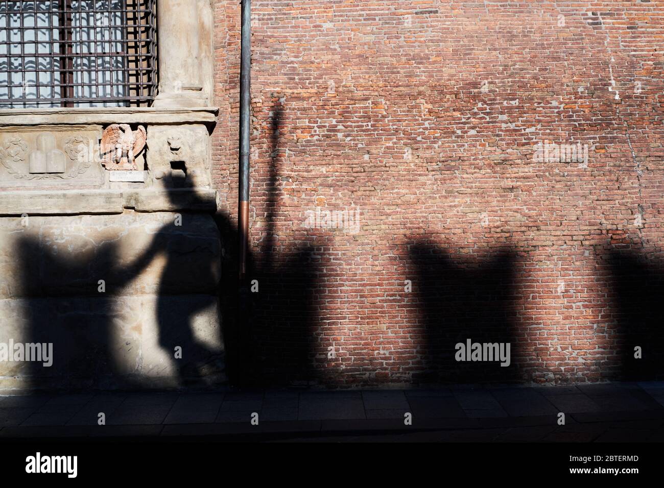 Shadow of the statue of Neptune on the brick wall of Palazzo d'Accursio, in the historic center of Bologna in Italy Stock Photo