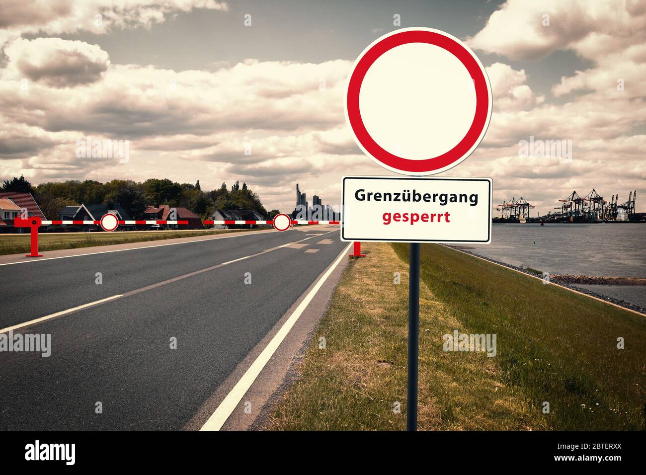 Border crossing in front of a container port, in the background a city silhouette. The inscription of the traffic sign: 'Grenzübergang gesperrt'. Traf Stock Photo