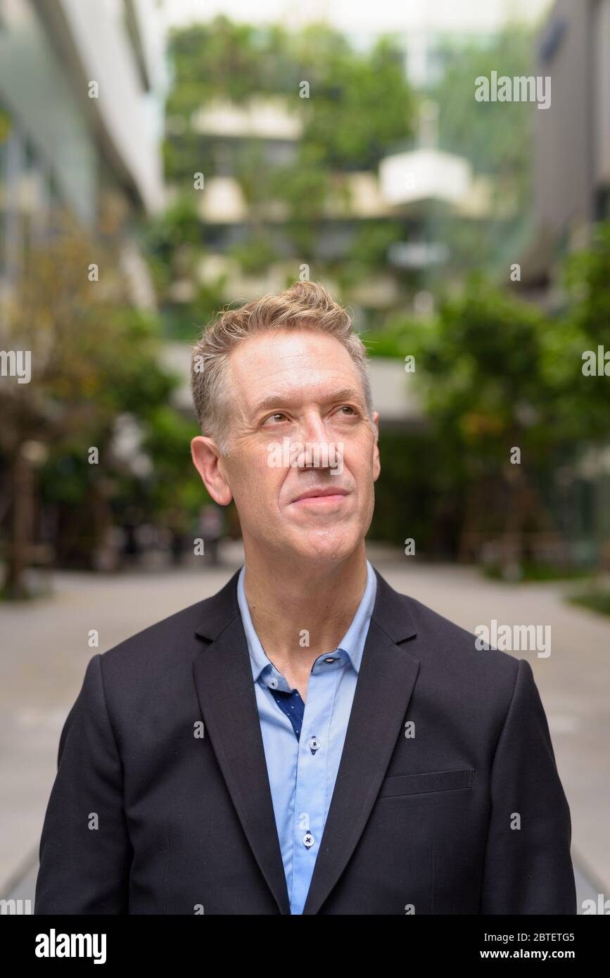 Mature businessman in suit thinking with nature in the city Stock Photo ...