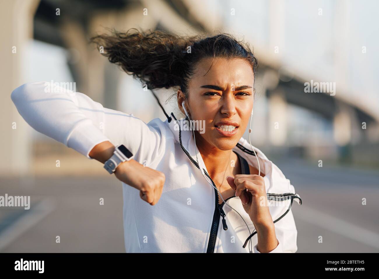 Strong young woman practicing boxing outdoors. Female boxer doing punches. Stock Photo