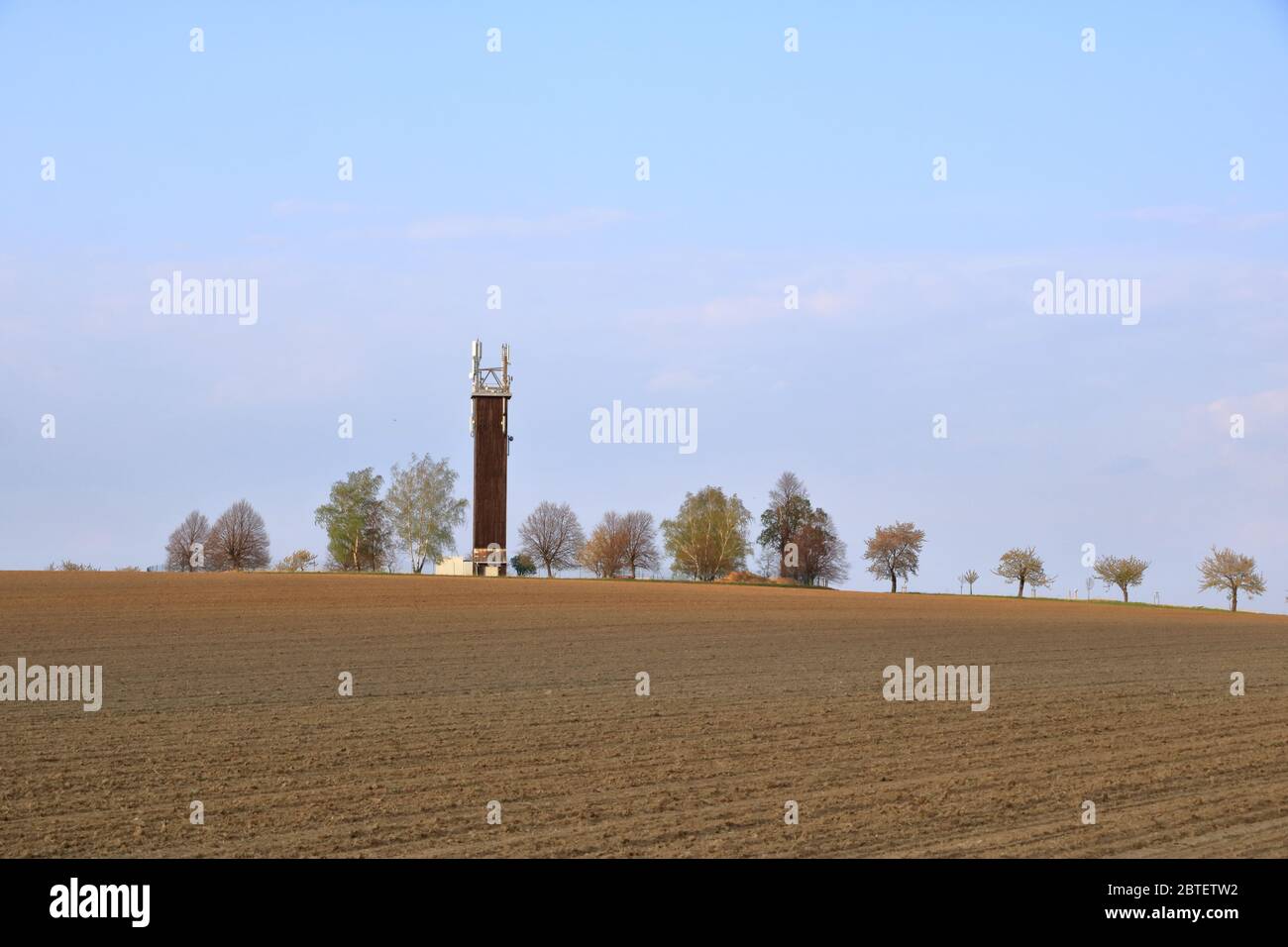 Wooden Telecommunication tower with transmitters. Cellular base station with transmitter antennas on telecommunication tower on against a blue sky wit Stock Photo