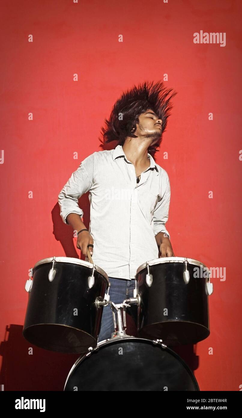 young drummer head banging isolated on red background Stock Photo