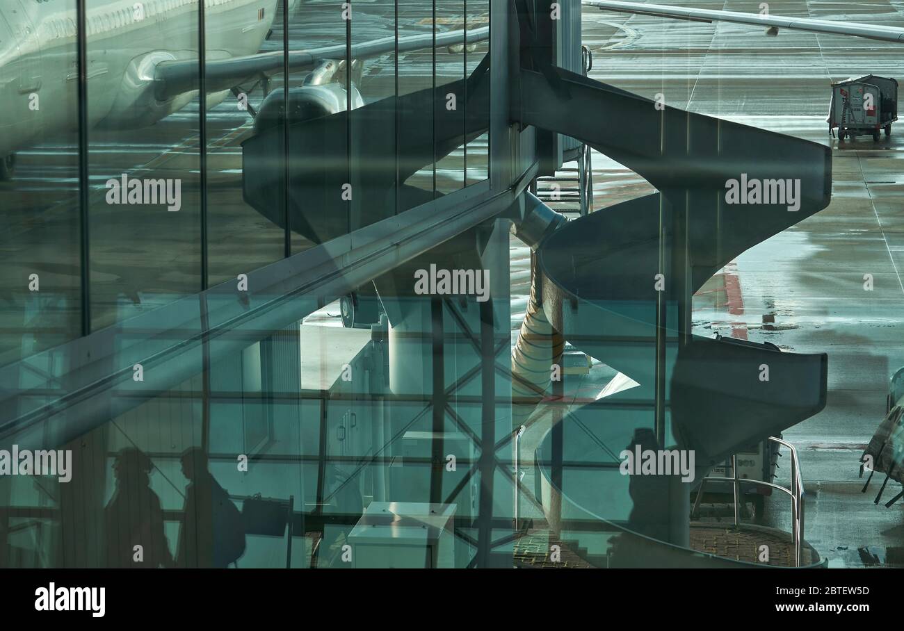 Airport in Brussels from the window capturing partially reflection of an aircraft, reflection from inside the airport hall with few silhouettes Stock Photo