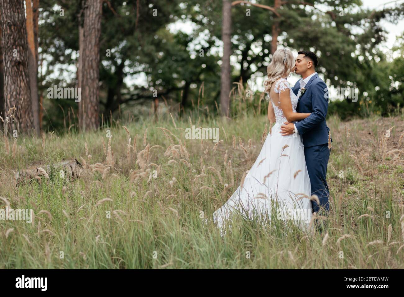 Kissing bride and groom standing in the park Stock Photo - Alamy