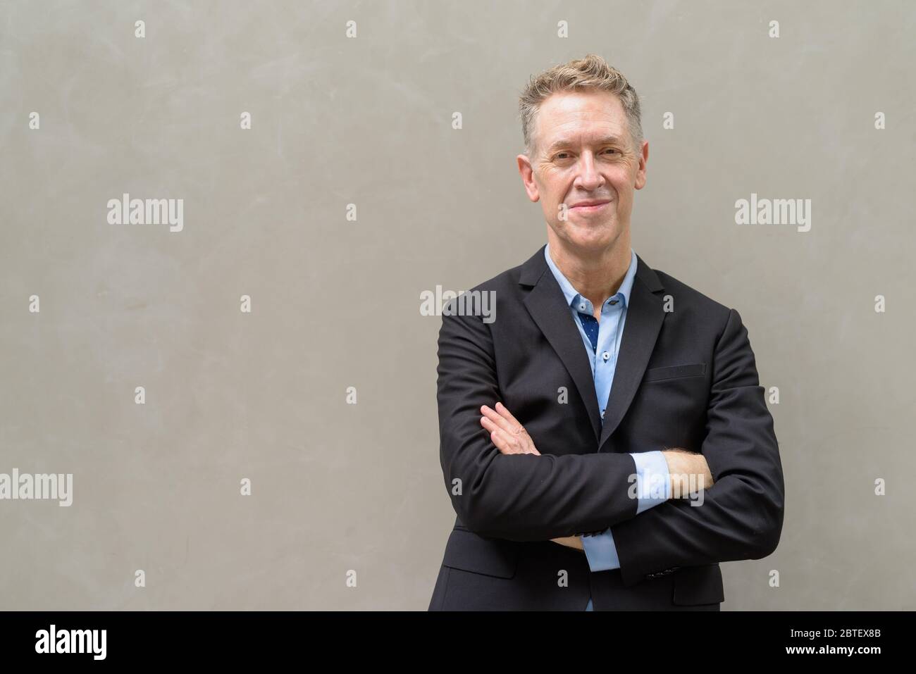 Mature businessman in suit with arms crossed outdoors Stock Photo - Alamy