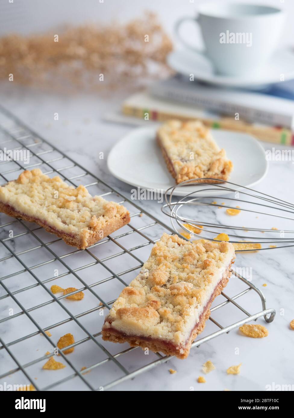 jam crumble bar on cake rack and white dish, decorated with egg whisk, selective focus. fresh homemade bakery concept Stock Photo