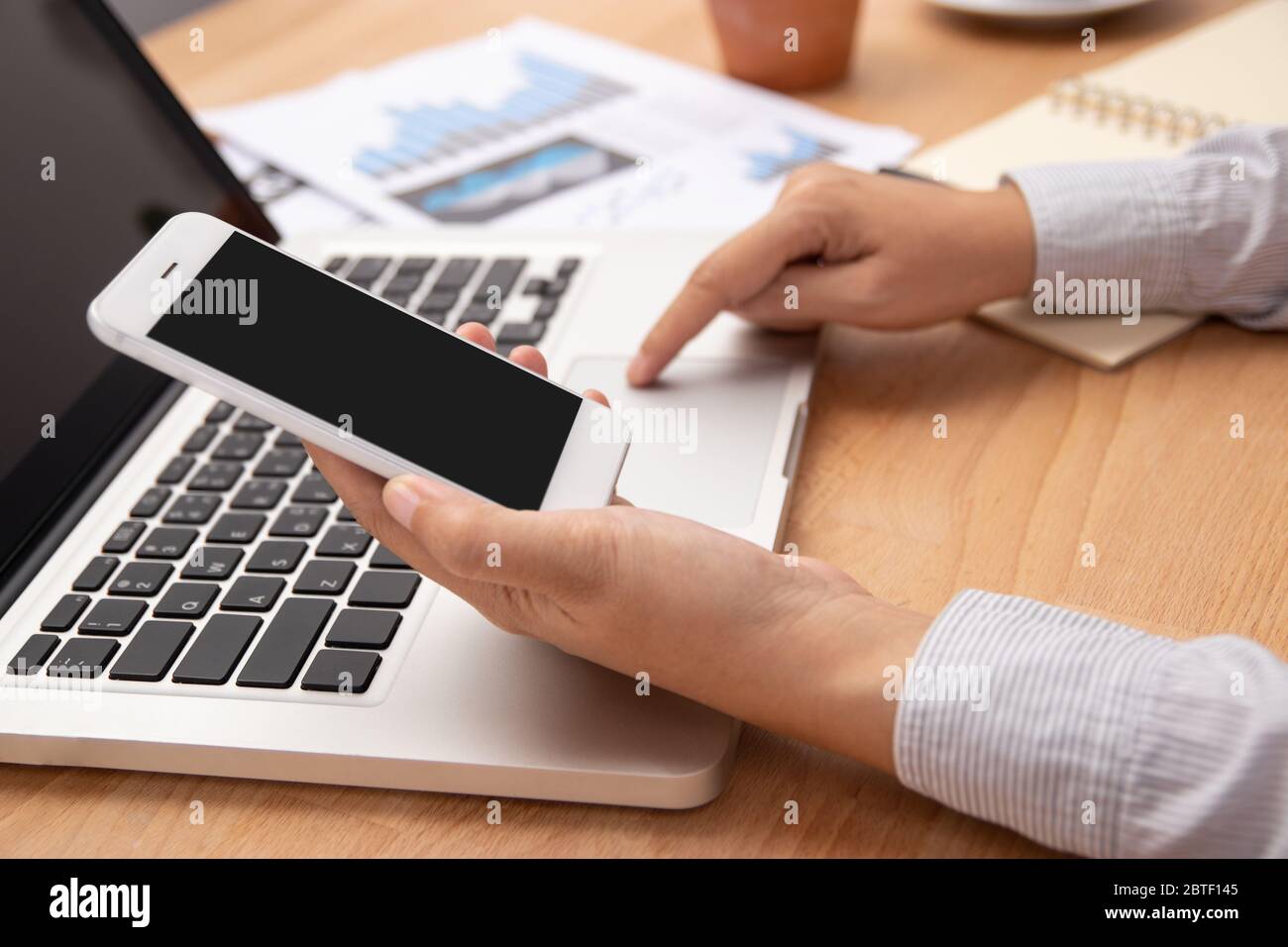 people working from home using smart phone and notebook laptop computer with blank black screen at workplace, anonymous face. new normal with internet Stock Photo