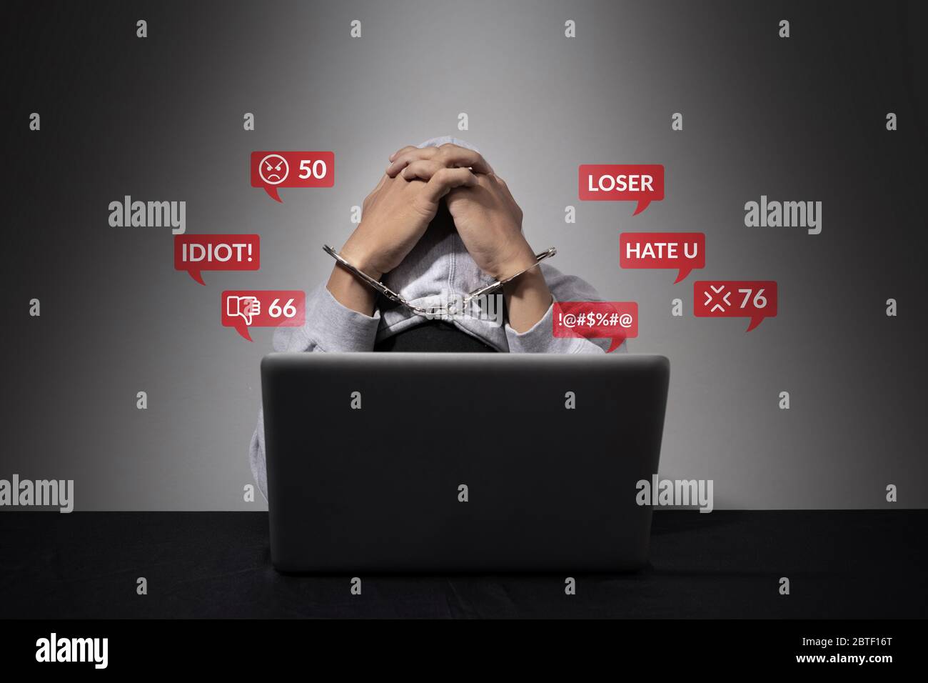cyber bullying concept. A handcuffed man is accused of being a social defendant, bending his head in front of the laptop computer with hate speech as Stock Photo