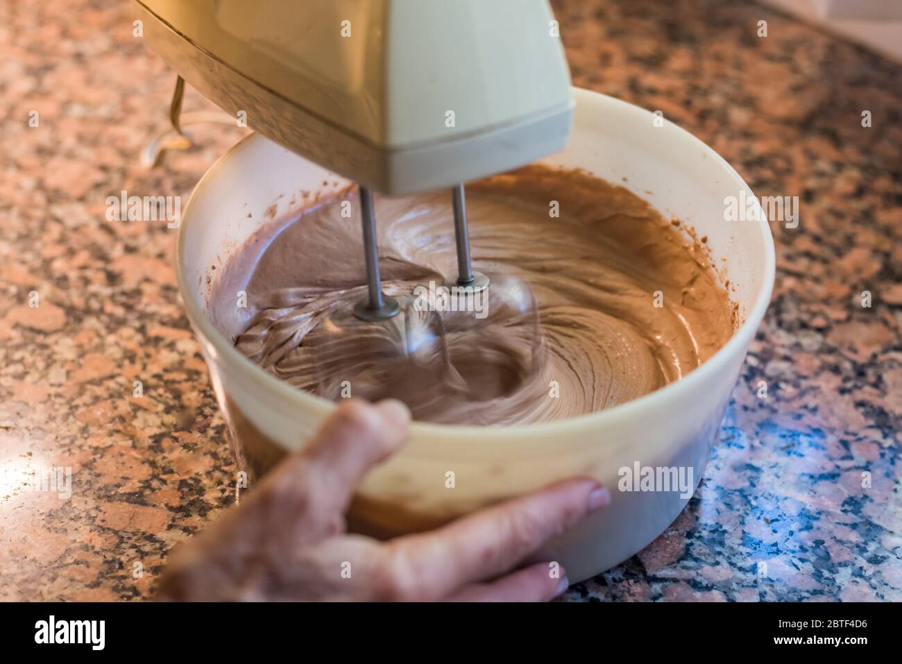 Woman's hand holding a bowl while mixing for a cake during quarantine Stock Photo Alamy