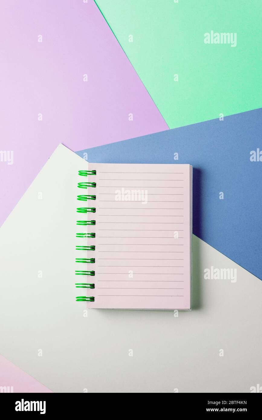 Open notebook with blank sheet and green spiral on a colorful pastel background. The concept of education, writing down ideas, plans. Place for text. Stock Photo