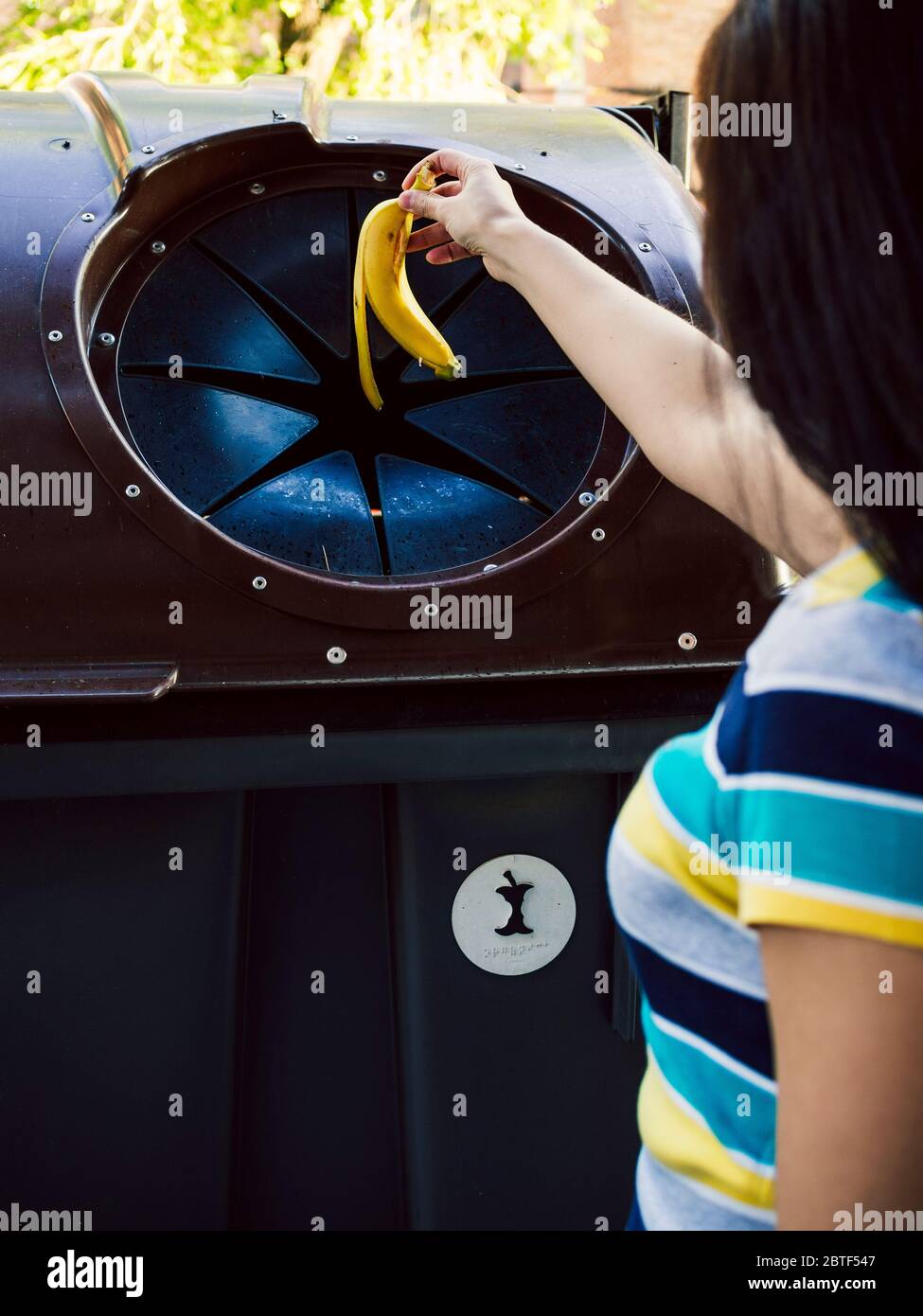 Woman throwing a banana peel in the trash. Recycling concept. Stock Photo