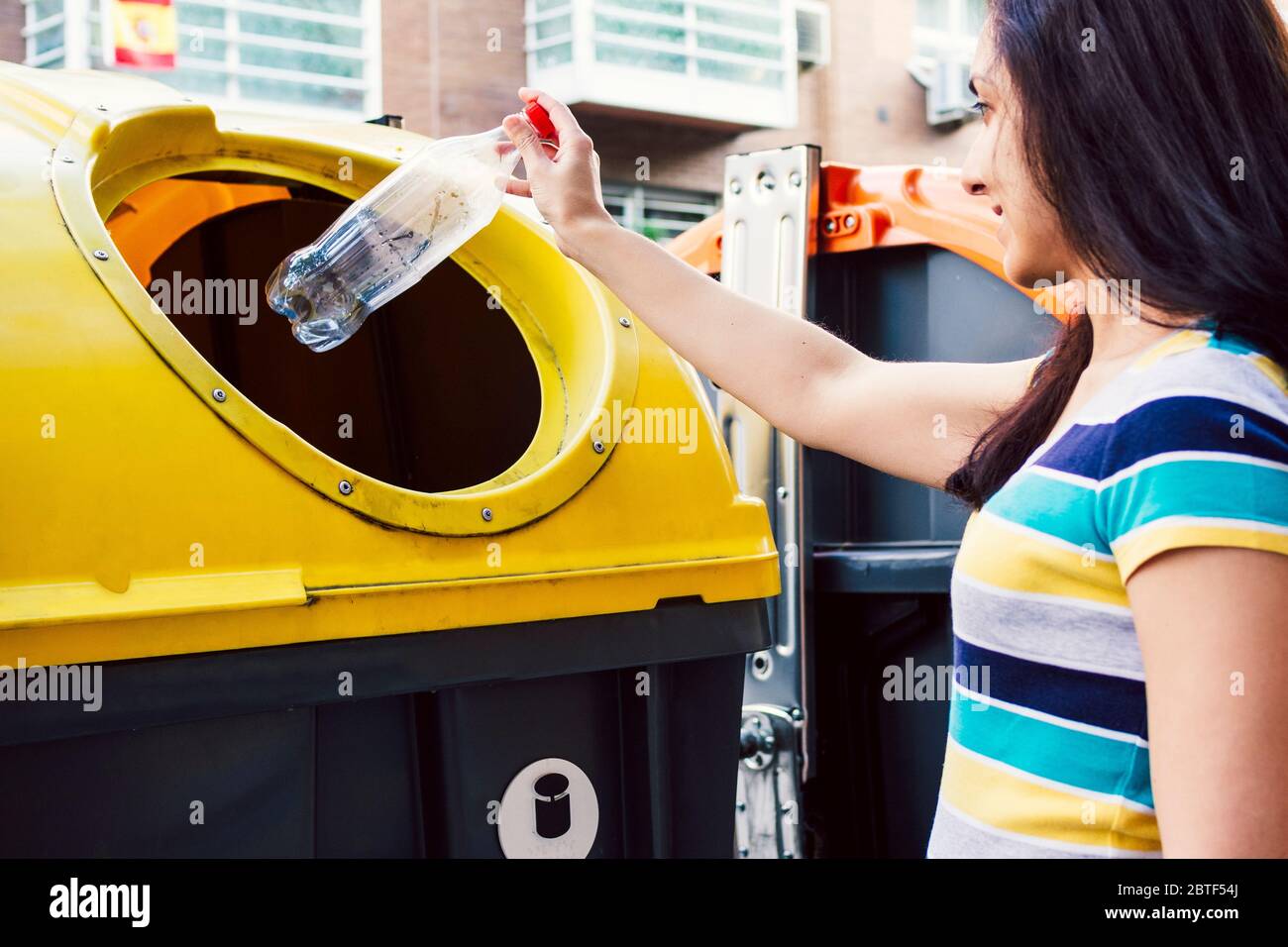 Woman throwing bottle in recycling bin. Recycling concept. Stock Photo