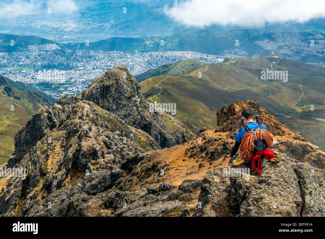 Mountain climber with ropes and walking sticks enjoying the view, making a phone call after reaching the Rucu Pichincha Volcano Peak, Quito, Ecuador. Stock Photo