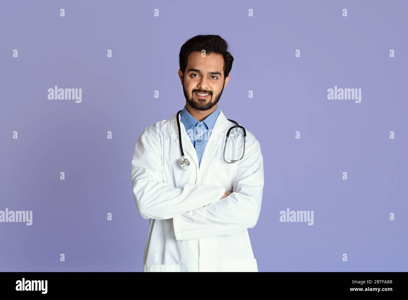 Confident Indian doctor in uniform crossing his arms on color background Stock Photo
