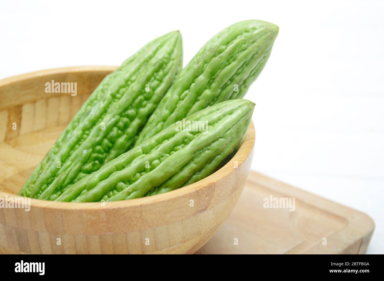 Green Organic Bitter melon in the wooden bowl. Bitter melon good for diabetic, can reduce Blood Sugar and can decrease Cholesterol Levels Stock Photo