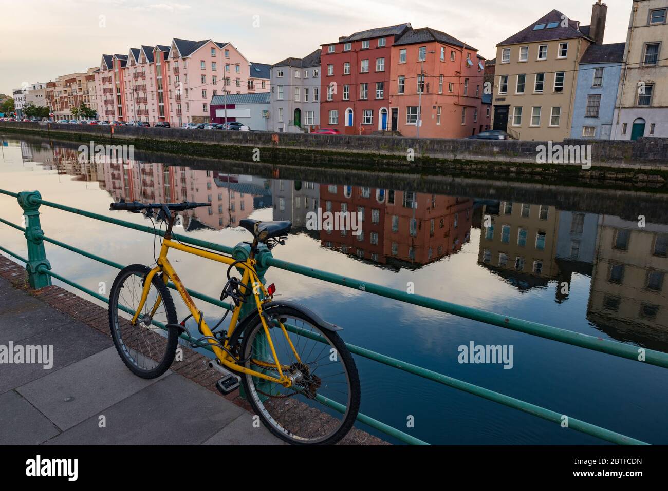 Old rusty Yellow mountian bicycle attached to metal gate railing by the river lee in Cork city Stock Photo
