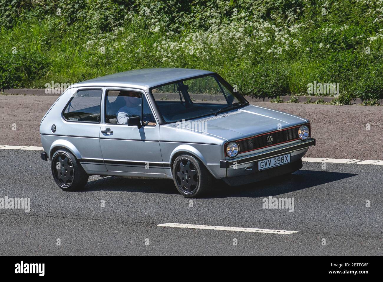 1982 silver Volkswagen Golf GTI; Vehicular traffic moving vehicles, cars driving vehicle on UK roads, motors, motoring on the M61 motorway highway in Manchester, UK Stock Photo