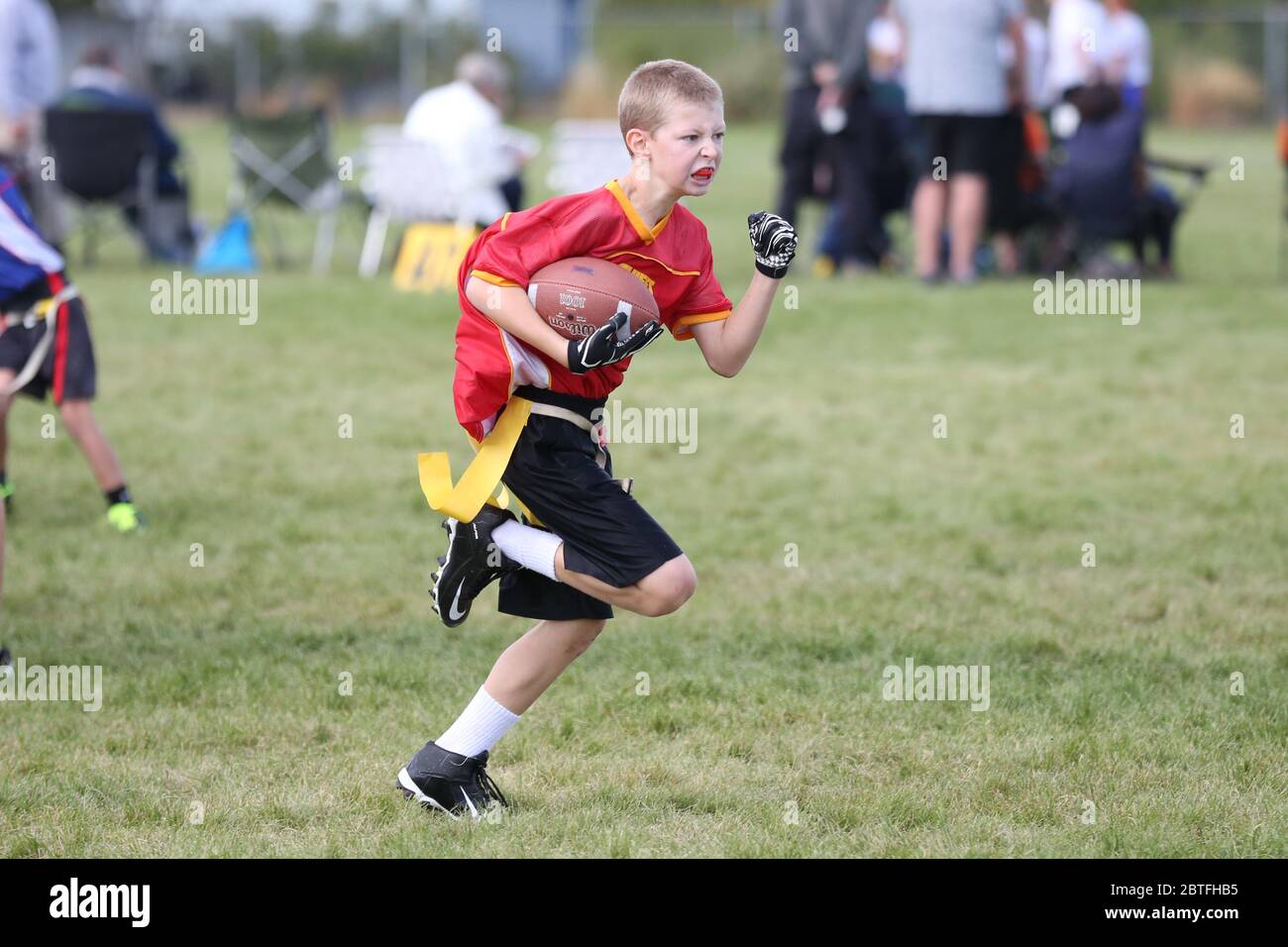 Youth flag football game action shot of player running with the football attempting to score a touchdown. Stock Photo