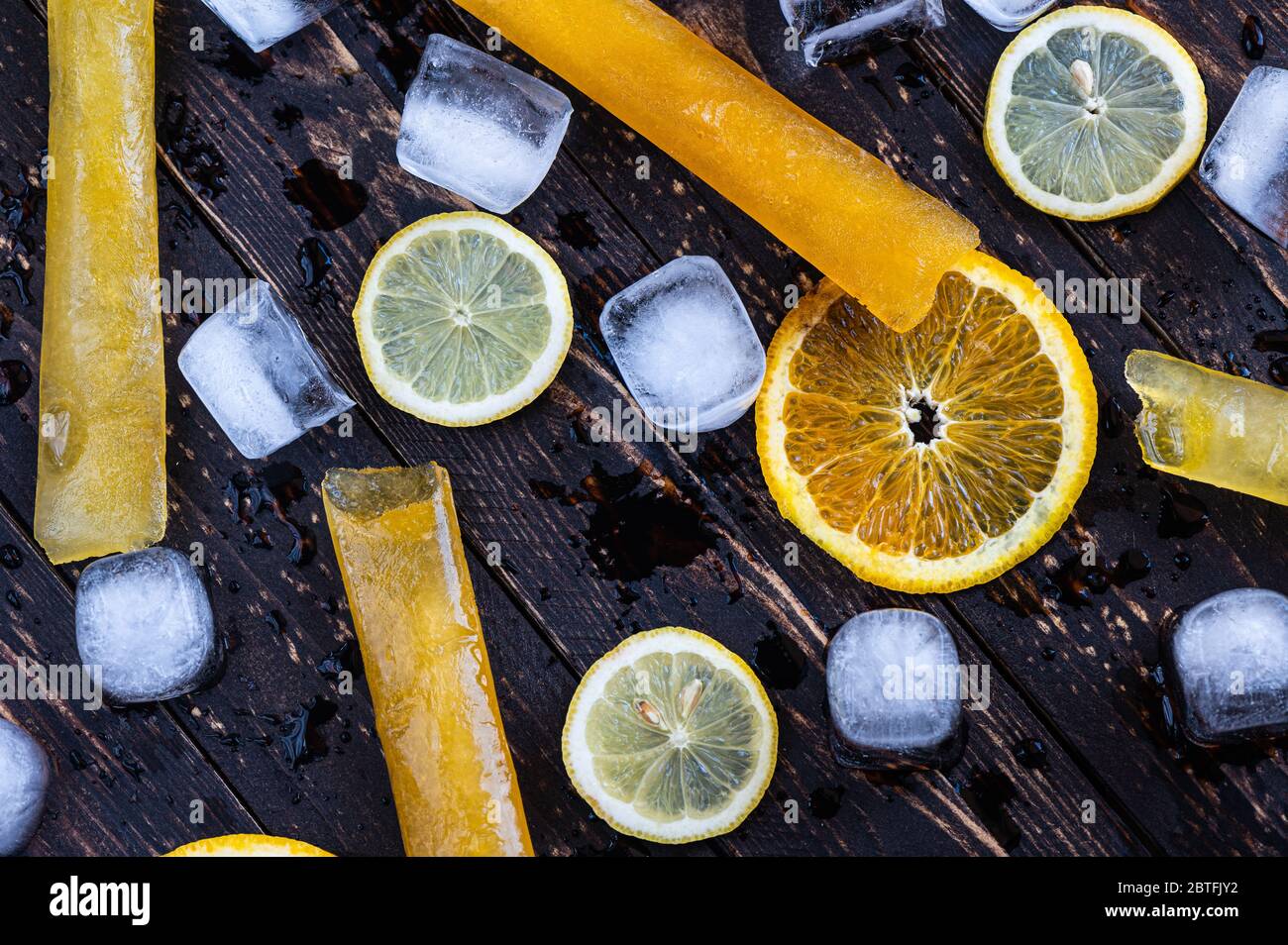 Close up of fruit ice lollies, lemon and orange slices and ice cubes Stock Photo